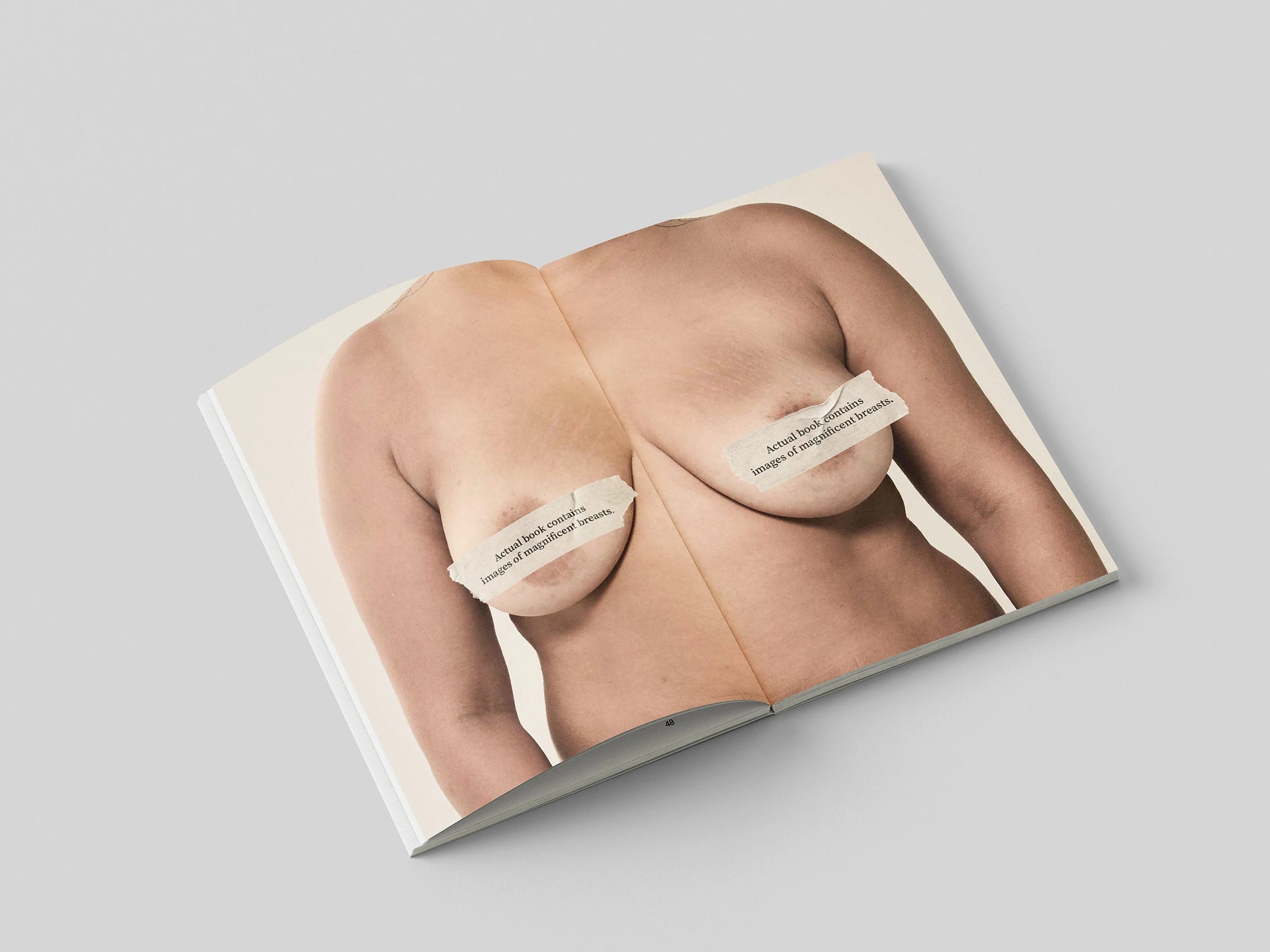 The Chests book open to a portrait of a bare chest with the nipples covered by the subject's printed quote